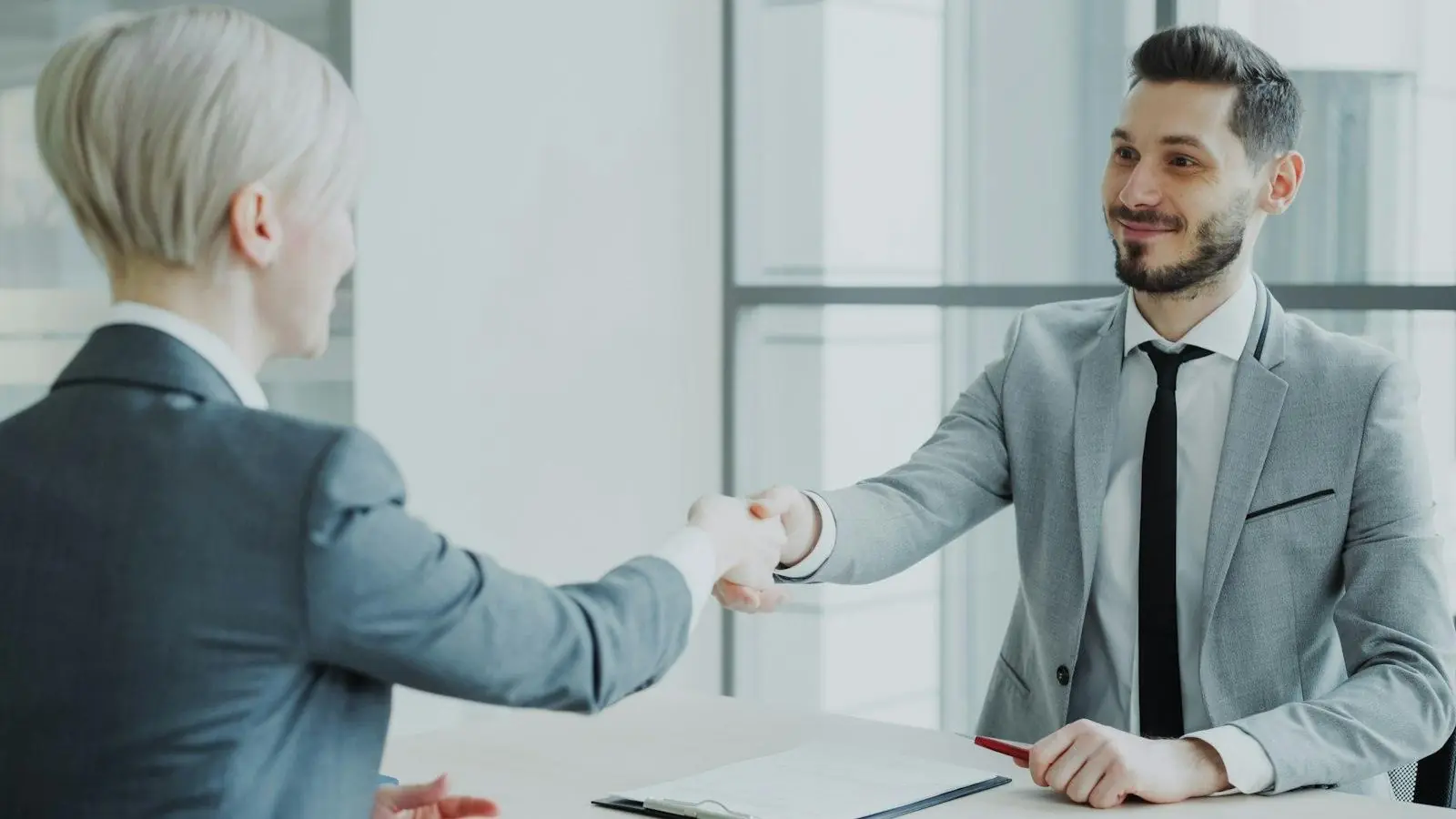 Deux personnes se serrent la main au-dessus d'un contrat