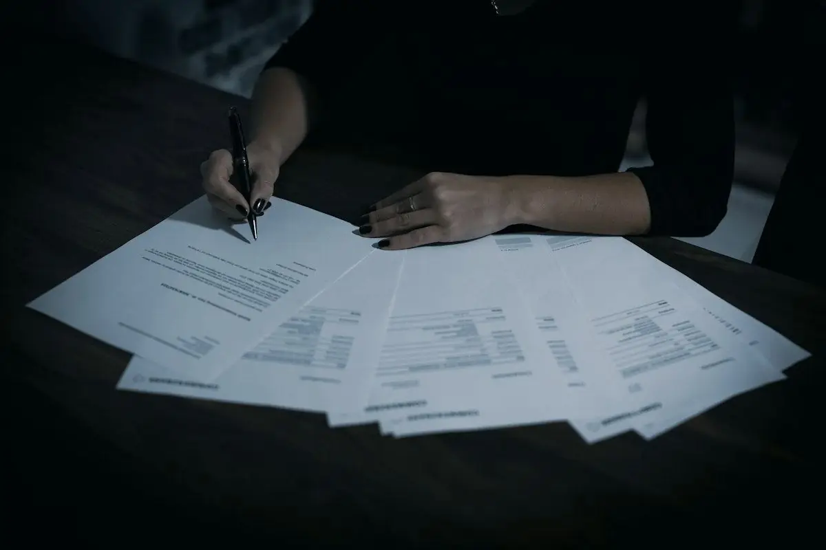 Mains qui signent des documents sur un bureau